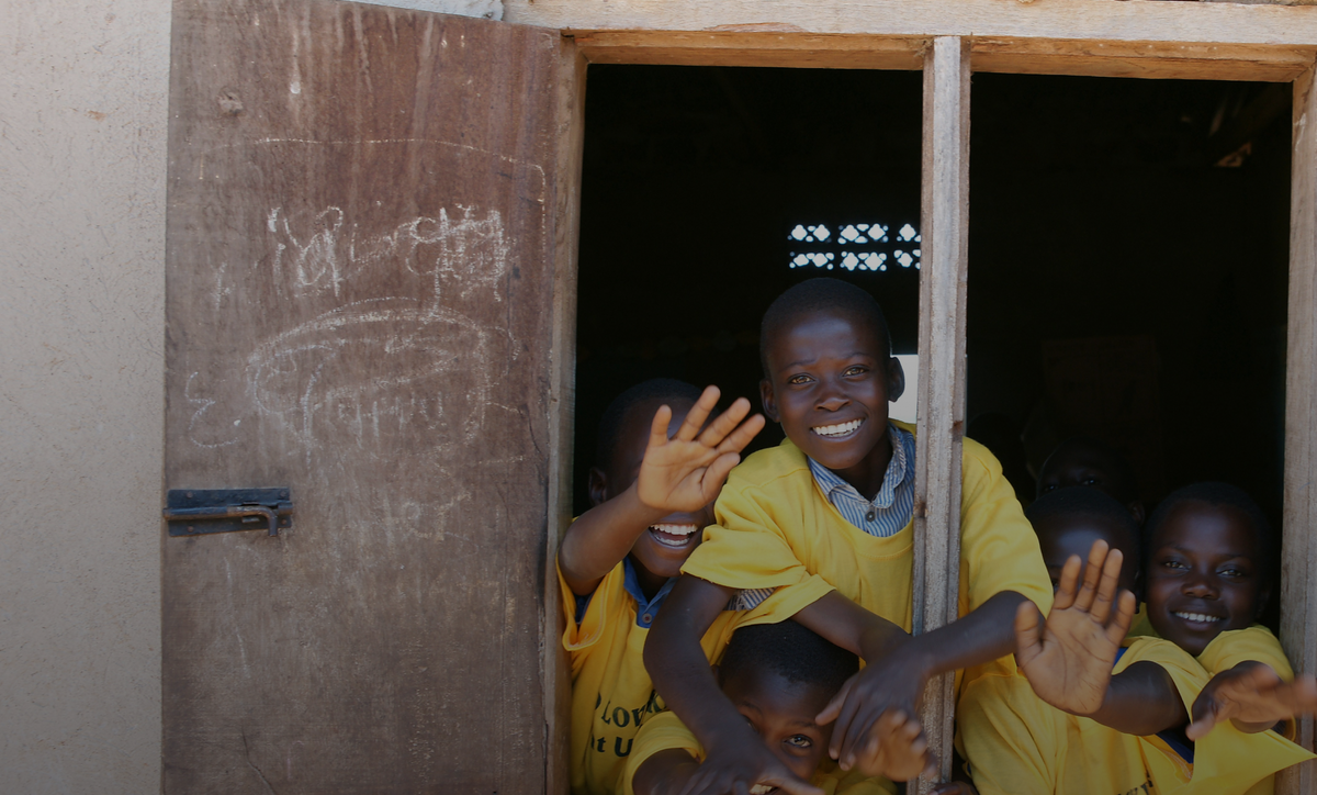 Children in Mali waving from a classroom window
